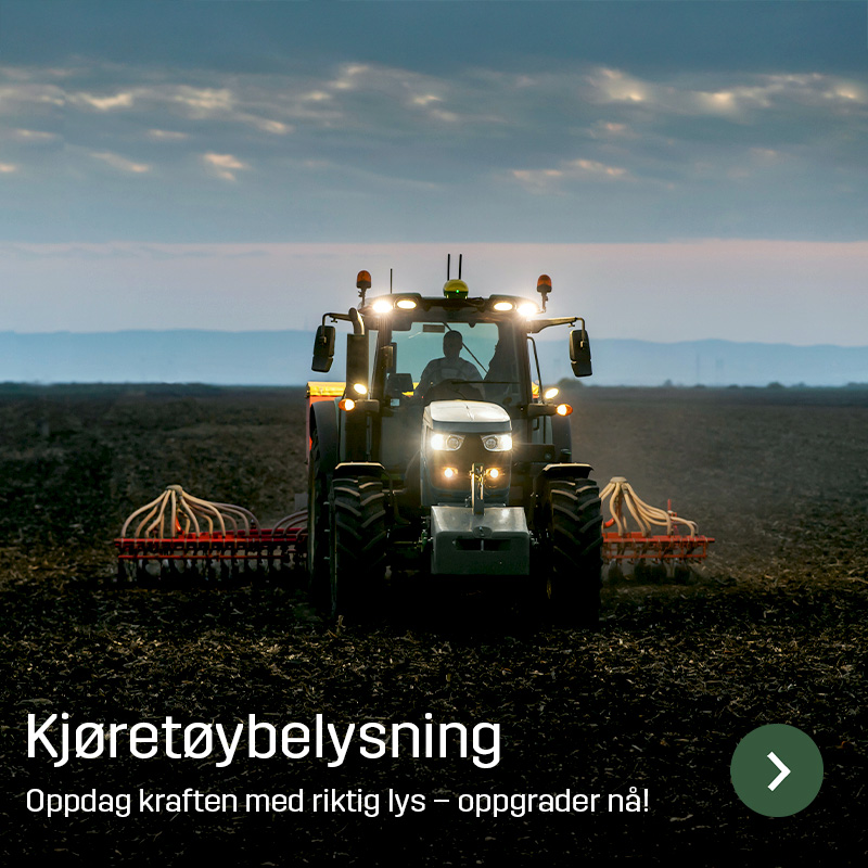 Traktor med tent arbeidsbelysning kjører på åkeren med et bredt redskap bak. Sagros kjøretøybelysning gir lys rundt landbruksmaskiner under arbeid på jordet.